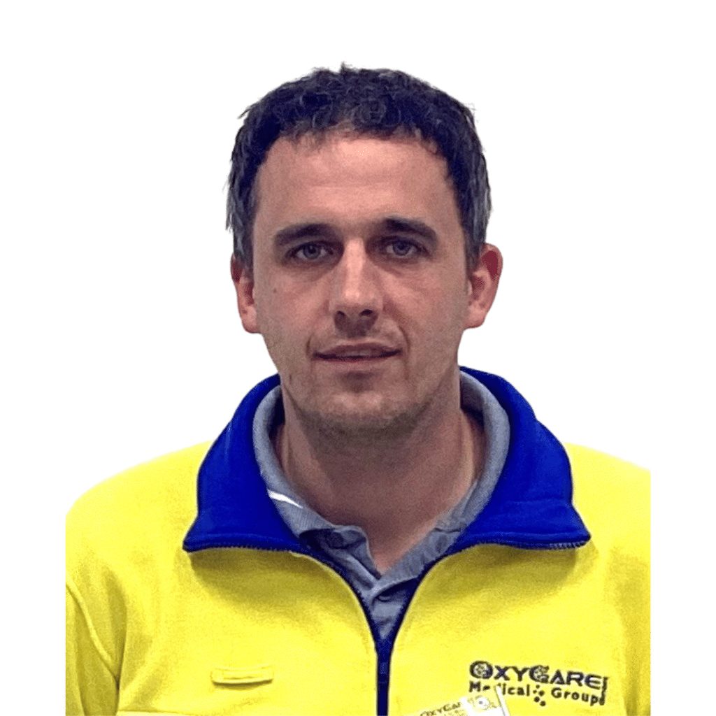 Foto von Oliver Schob, Mitarbeiter von OxyCare. Er trägt ein gelbes Hemd mit dem OxyCare Logo und schaut freundlich in die Kamera.